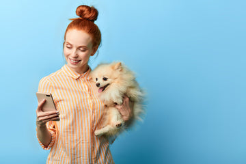 Woman holding her phone in one hand while cradling her dog