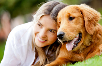 Close up of woman and dog laying on the grass
